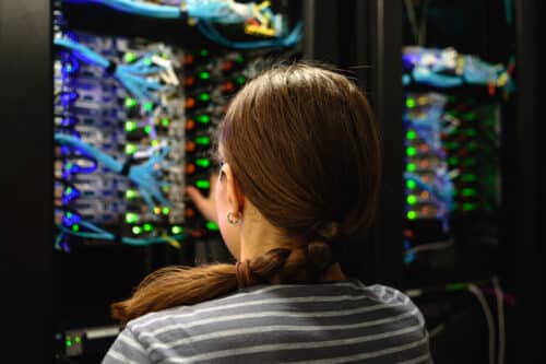 female IT professional examining servers in server room in effort to resolve challenges for nonprofit client