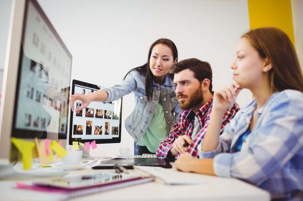 employees discussing ideas at work on computer with the help of outsourced it support